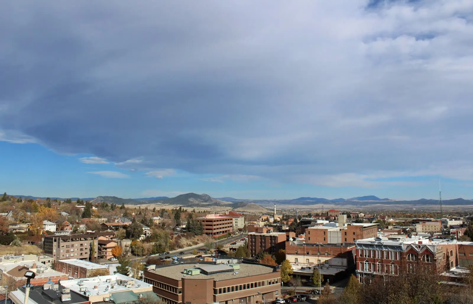 Downtown skyline of historic brick buildings beneath a wide sky, mountains beyond
