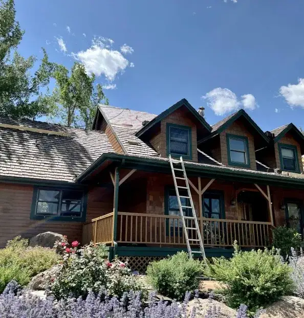 Wood-sided two-storey home with dormers and a weathered wood shake roof