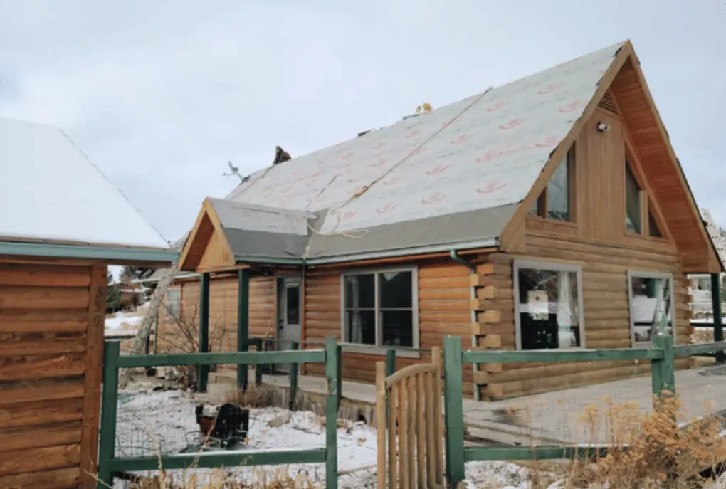 Log home roof covered in new underlayment during winter