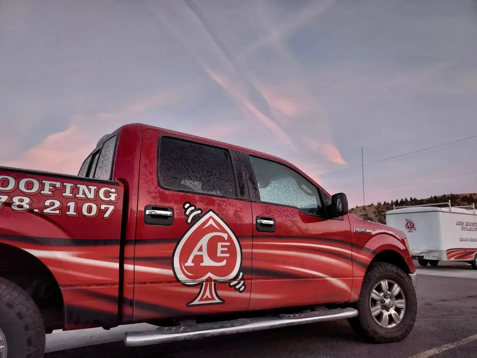 Red Ace Roofing pickup with the ace of spades logo at sunset