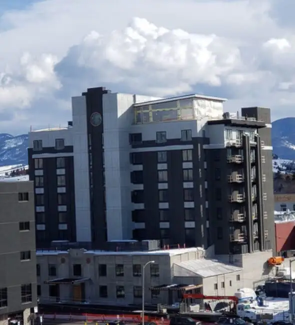 Multi-storey hotel with a dark and white facade in front of snow-covered mountains
